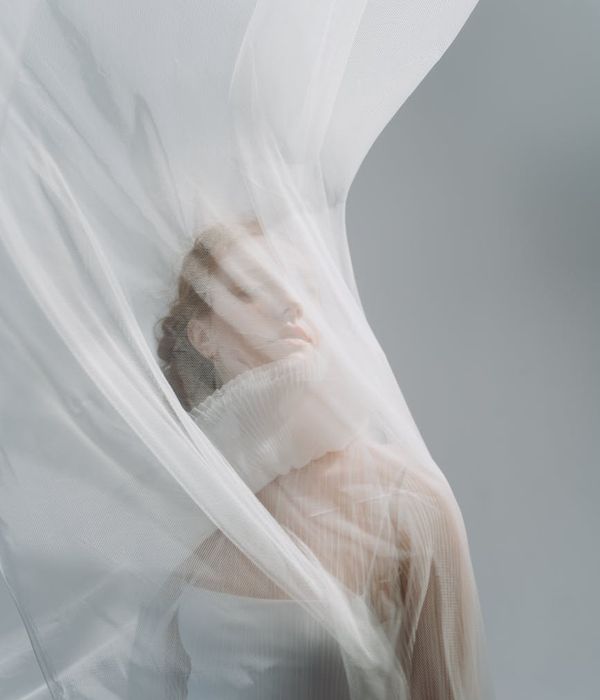 Woman performing a gentle, flowing movement in a bright, minimalist space.